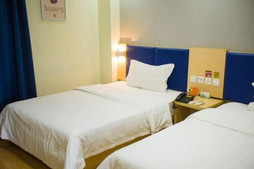 a hotel room with two beds and a telephone at 7 Days Inn Jinan Changqing Jingshi West Road Center in Jinan