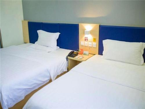 a hotel room with two beds and a night stand at 7 Days Inn Jinan Changqing Jingshi West Road Center in Jinan