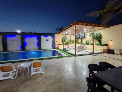 a swimming pool in a house with chairs around it at Wonder Villa in Al Rama