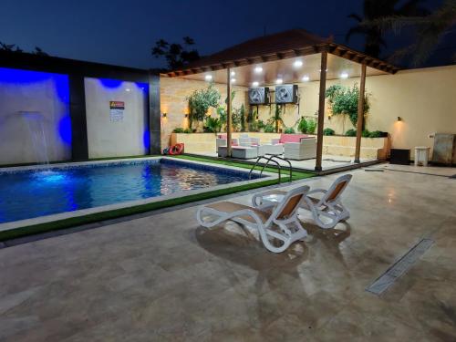 a swimming pool with two lounge chairs next to it at Wonder Villa in Al Rama
