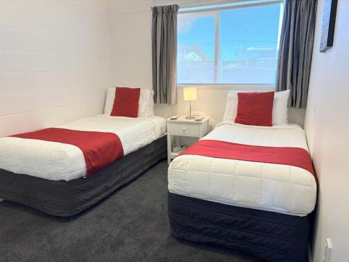 two beds in a room with a window at Baileys At The Beach in Whitianga