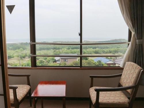 two chairs and a table in front of a large window at Hotel New Otsuka in Shirako