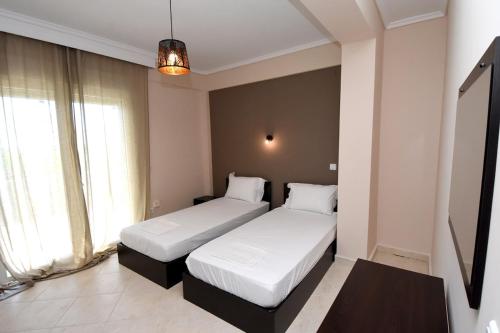 two beds in a room with two windows at A&G Country House, Potamos Epanomis Beach in Epanomi