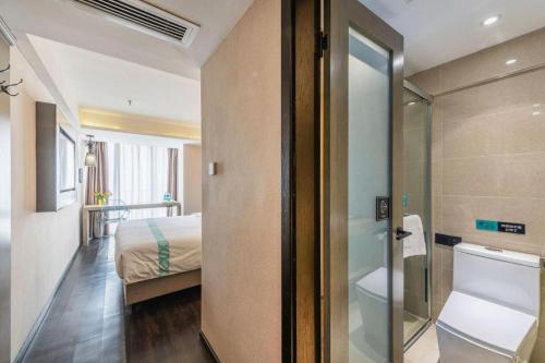 a bedroom with a bed and a glass door to a bathroom at Xana Lite Guiyang Huaguoyuan Shuangzi Towers in Guiyang