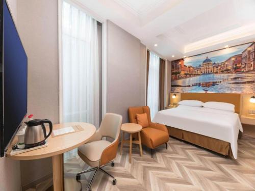 a hotel room with a bed and a table and chairs at Vienna Suzhou Oriental Gate Jinji Lake in Suzhou