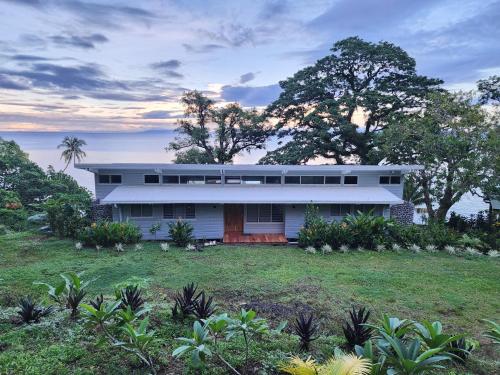 a white house sitting on top of a lush green field at Waterfront modern 3br home Vale Ni Vonu in Nggathavulu