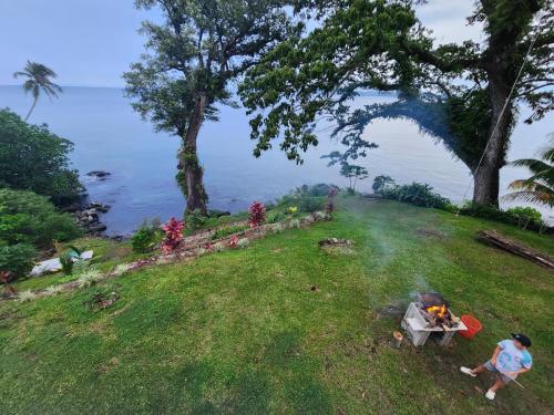 a woman standing next to a grill on a grass field at Waterfront modern 3br home Vale Ni Vonu in Nggathavulu
