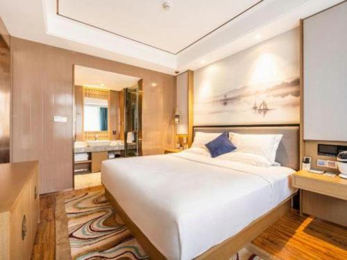 a bedroom with a large white bed and a bathroom at East Queen Hotel (Xi'an Beimen Metro Station) in Xi'an