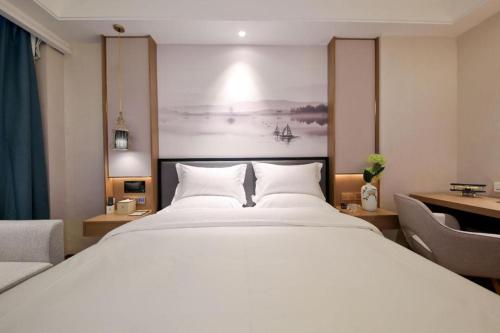 a bedroom with a large white bed and a desk at East Queen Hotel (Xi'an Beimen Metro Station) in Xi'an