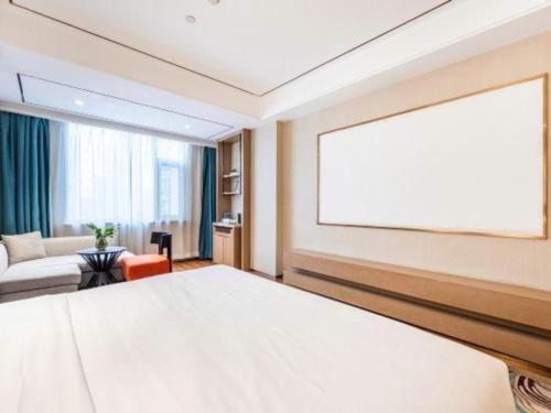 a bedroom with a large white bed and a couch at East Queen Hotel (Xi'an Beimen Metro Station) in Xi'an