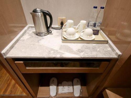 a counter top with a coffee pot and dishes on it at East Queen Hotel (Xi'an Beimen Metro Station) in Xi'an