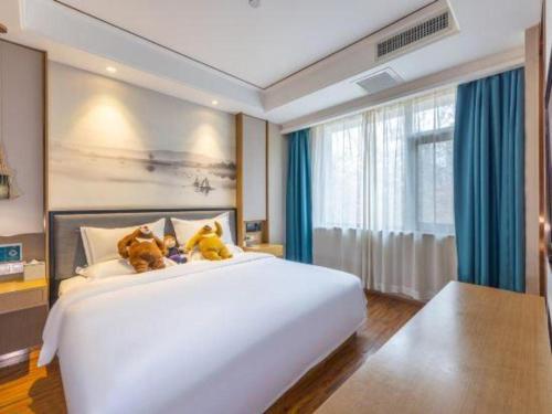 a bedroom with a large white bed with teddy bears on it at East Queen Hotel (Xi'an Beimen Metro Station) in Xi'an