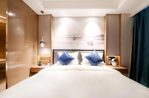 a bedroom with a large white bed with blue pillows at East Queen Hotel (Xi'an Beimen Metro Station) in Xi'an