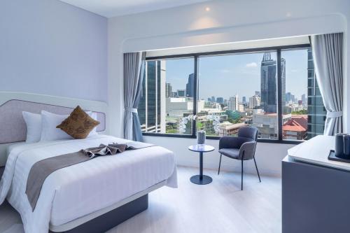 a hotel room with a bed and a large window at Queensland Hotel Bangkok in Bangkok