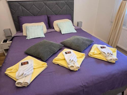 a purple bed with yellow towels on top of it at Apartman Marjanović Palić in Palić