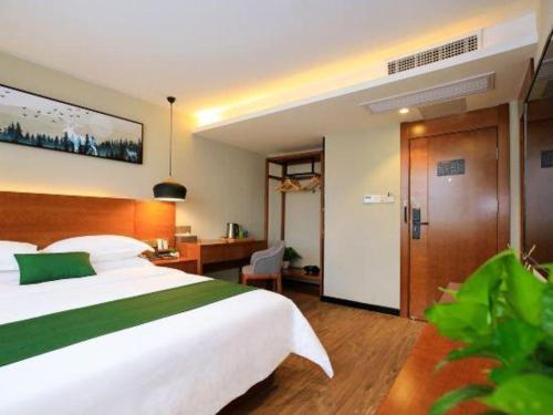 a bedroom with a large white bed and a desk at Immersing Hotel Guilin Two Rivers and Four Lakes Dongxi Alley in Guilin
