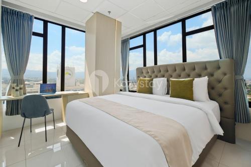 Savya ApartHotel by Kozystay - Bandung City في باندونغ: غرفة نوم بها سرير ومكتب ونوافذ