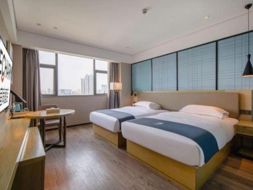 a hotel room with two beds and a desk at Echarm Hotel Nanning Chaoyang Square River View in Nanning