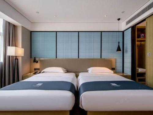 two beds in a hotel room with windows at Echarm Hotel Nanning Chaoyang Square River View in Nanning