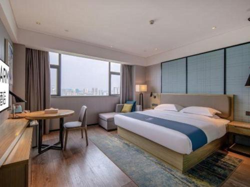 a hotel room with a large bed and a desk at Echarm Hotel Nanning Chaoyang Square River View in Nanning