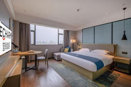 a hotel room with a large bed and a desk at Echarm Hotel Nanning Chaoyang Square River View in Nanning