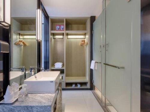 a bathroom with a white sink and a shower at Echarm Hotel Nanning Chaoyang Square River View in Nanning