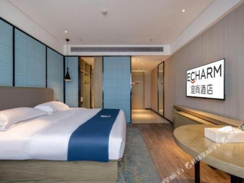 a bedroom with a large bed and a table at Echarm Hotel Nanning Chaoyang Square River View in Nanning