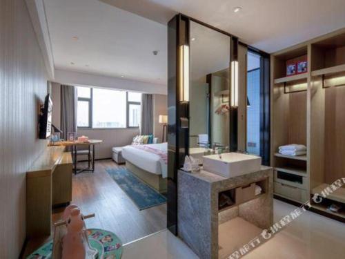 a bathroom with a bed and a sink in a room at Echarm Hotel Nanning Chaoyang Square River View in Nanning