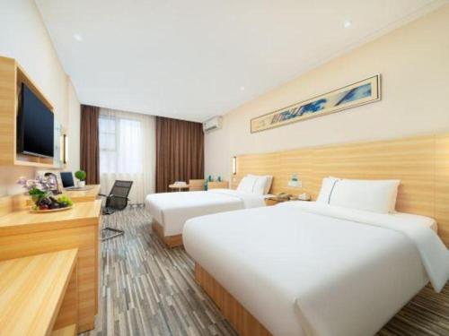 a hotel room with two beds and a television at City Comfort Inn Nanning Wuyi Fude in Nanning