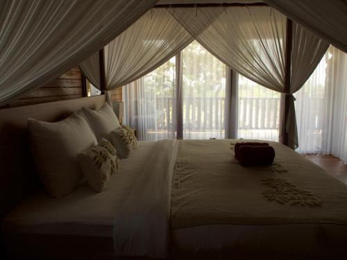 a bedroom with a large bed with a large window at Anna Villas by Sumba-Beach in Memboro