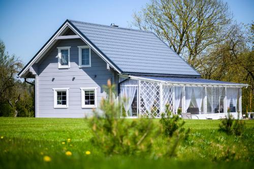 a white house with a greenhouse in a field at Arimaičių kaimo sodyba in Arimaičiai