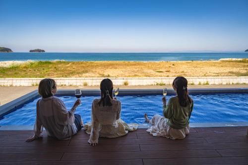three women sitting on a deck looking at the ocean at SETO CLAS TSUDA THE Beach RESORT B in Yoshimi