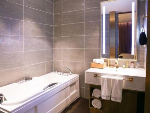 a bathroom with a tub and a sink and a mirror at James Joyce Coffetel Shijiazhuang Wanda Plaza Tangu Metro Station in Shijiazhuang