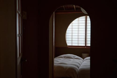 a bedroom with a window and a bed with white sheets at unsui 武雄蓬莱町 雲水 in Takeo