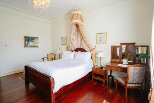 a bedroom with a bed and a desk at Dalat Palace Heritage Hotel in Da Lat