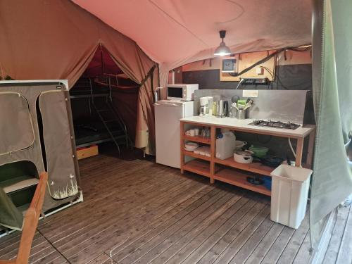 a small tent with a kitchen and a refrigerator at Camping Onlycamp le Martinet in Villard-Saint-Sauveur