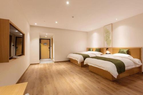 two beds in a large room with wooden floors at Green Tree Inn Nanchang Zhongshan Road Bayiguan in Nanchang