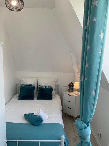 1 dormitorio con 1 cama con cortina azul en Villa Odette beach, en Villers-sur-Mer