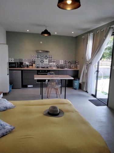 Cette chambre comprend un lit, une table et une cuisine. dans l'établissement L Essentiel Studio cllimatisé A pied Rivière, Marché,Voie Verte, à Ruoms