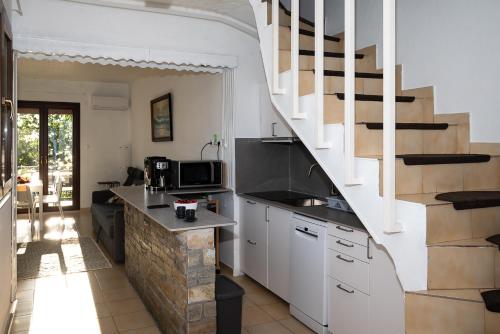 a kitchen with white cabinets and a spiral staircase at Step to Paradise in Pelion in Agios Ioannis Pelio