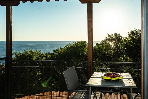 a table with a plate of food on a balcony with the ocean at Step to Paradise in Pelion in Agios Ioannis Pelio