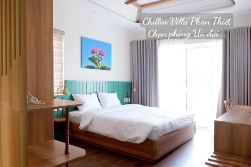 a bedroom with a bed and a table and a window at Chillin Villa Novaworld Phan Thiet in Bình Tú