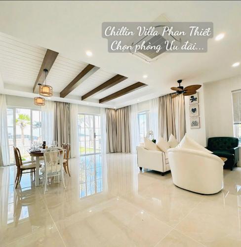 a living room with white furniture and a table at Chillin Villa Novaworld Phan Thiet in Bình Tú