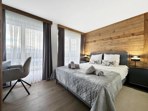 a bedroom with a bed and a desk and windows at Alpine Pearl - Panoramic Mountain Views - Aminona in Aminona