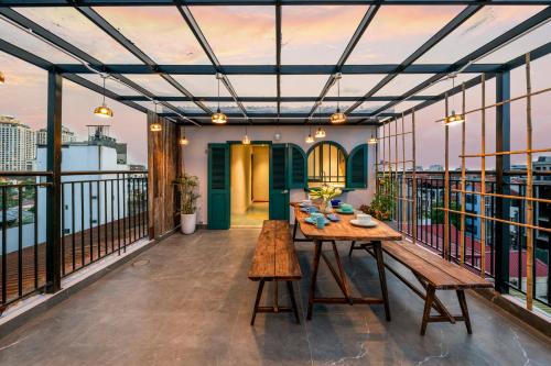 a patio with a wooden table and benches on a balcony at Tranquility Suites Westlake in Hanoi
