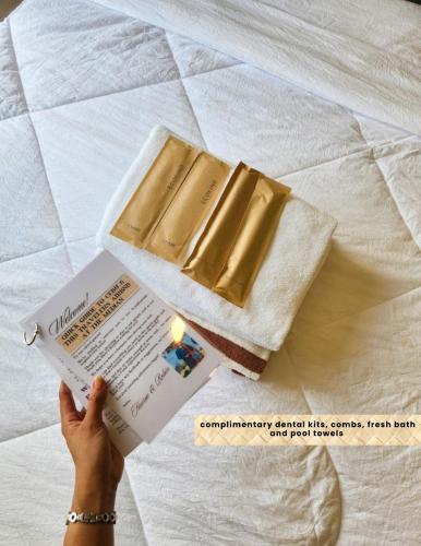 a person holding a book and a box on a bed at The Traveller's Haven at the Median in Cebu City