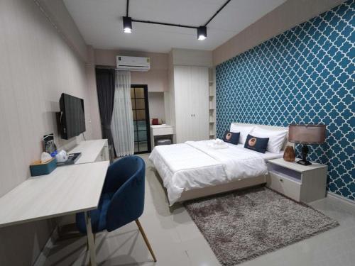a hotel room with a bed and a desk and a desk at RoomQuest Prachin Buri Rojana in Si Maha Phot