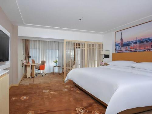 a bedroom with a large white bed and a desk at Vienna Hotel Chengdu Exhibition Center In Time City in Chengdu