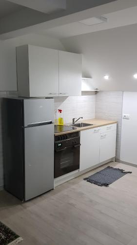 a kitchen with white cabinets and a black stove at Apartmani Kriva Drina in Okletac