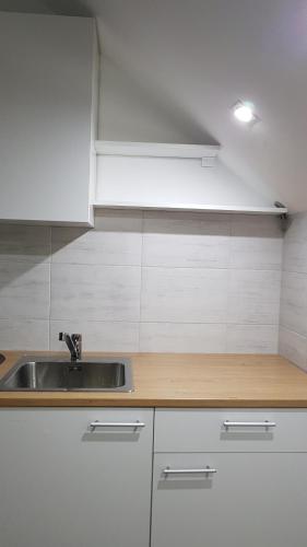 a kitchen with a sink and white cabinets at Apartmani Kriva Drina in Okletac